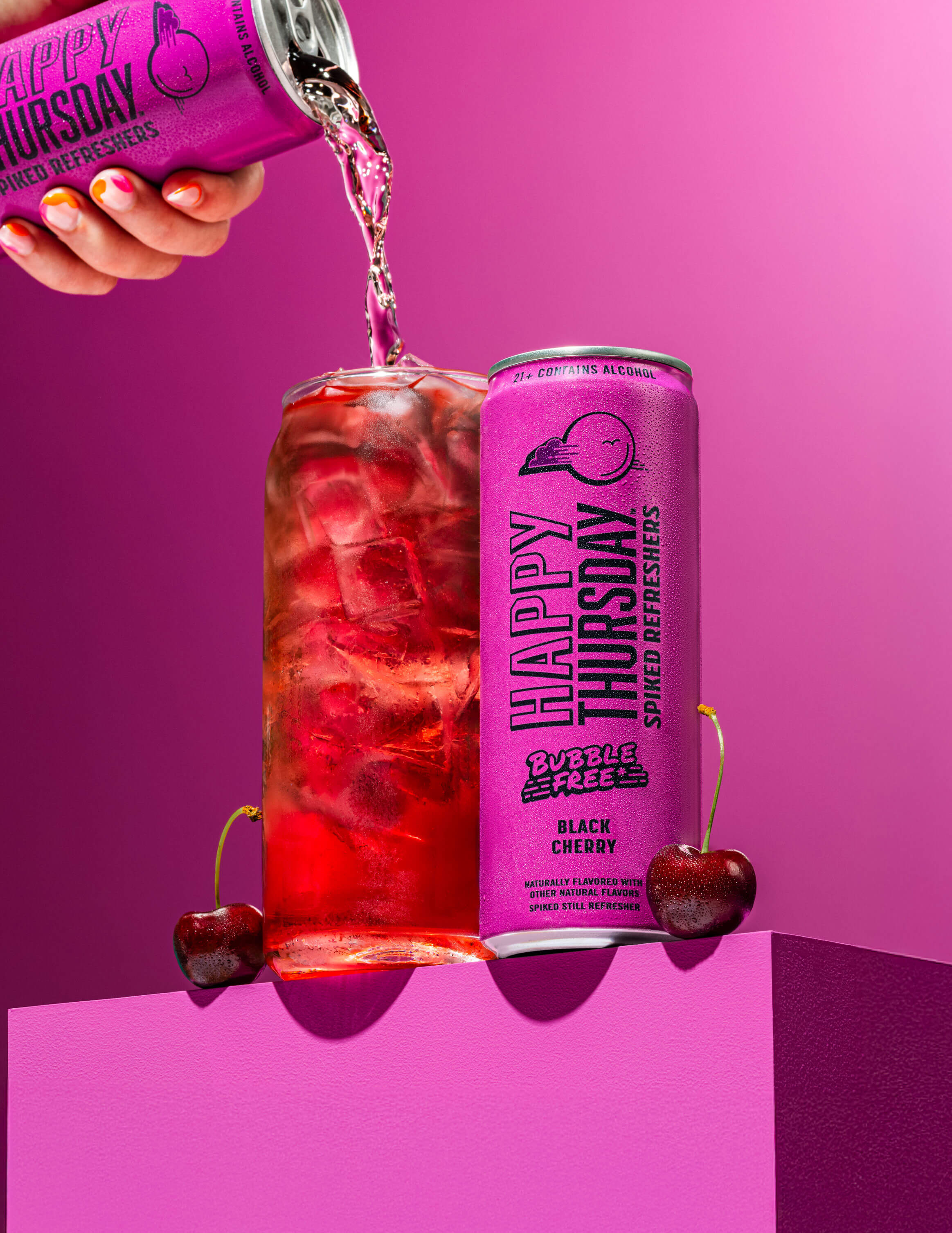 A can of Happy Thursday Raspberry dragonfruit Refresher is poured over ice into a glass, with Raspberry dragonfruit on a pink background.