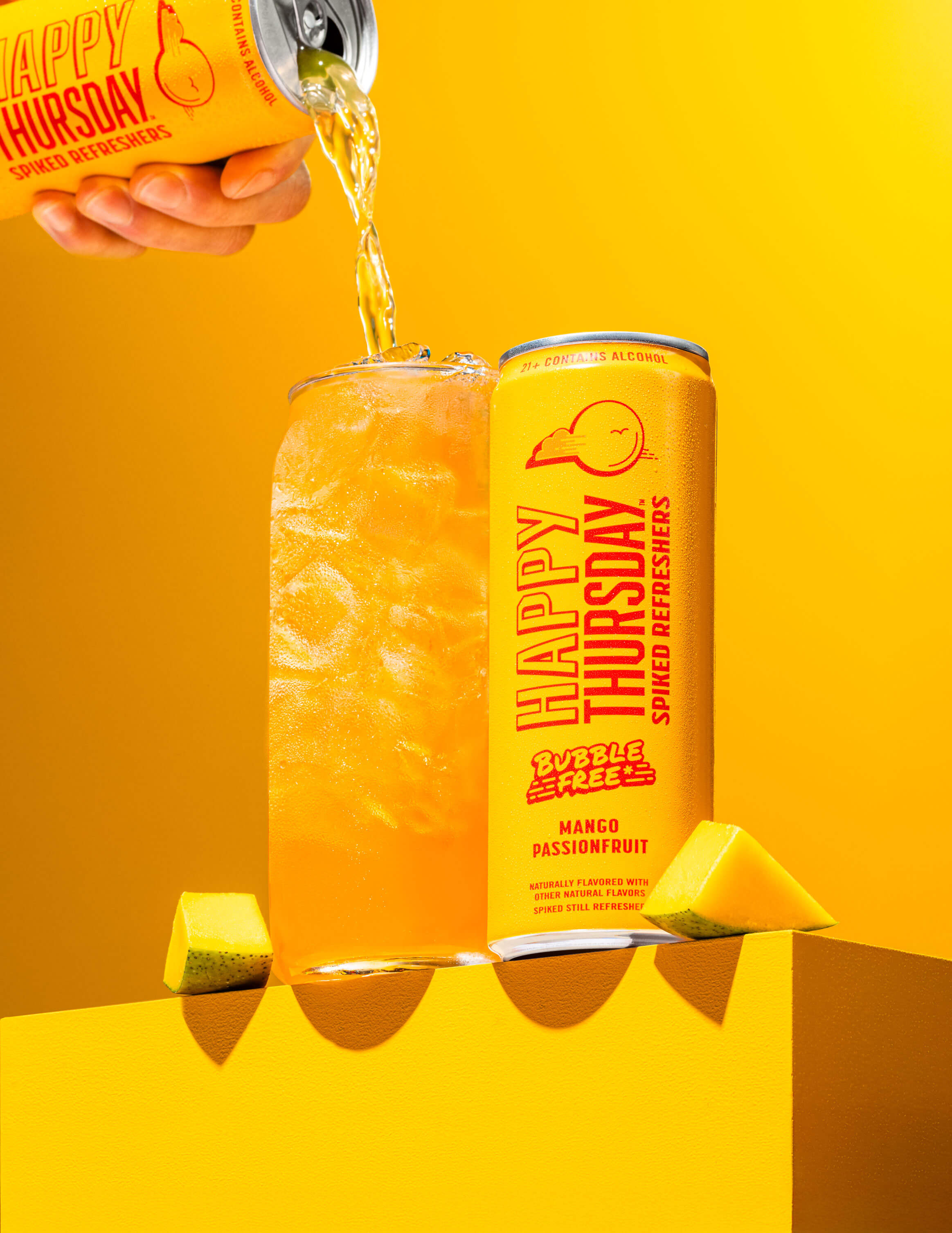 A can of Happy Thursday Mango Passionfruit Refresher is poured over ice into a glass, with Mango Passionfruit on a orange background.